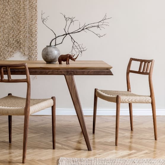 Minimalist dining table with wooden chairs and a simple vase centerpiece.